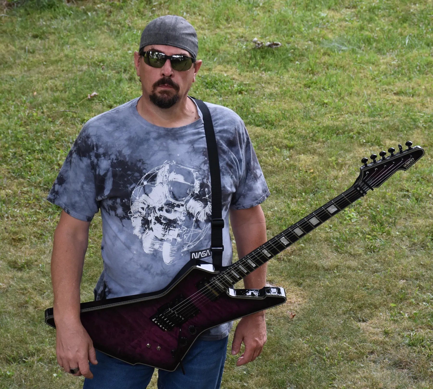 Ace Parlier holding an Explorer-style guitar outdoors