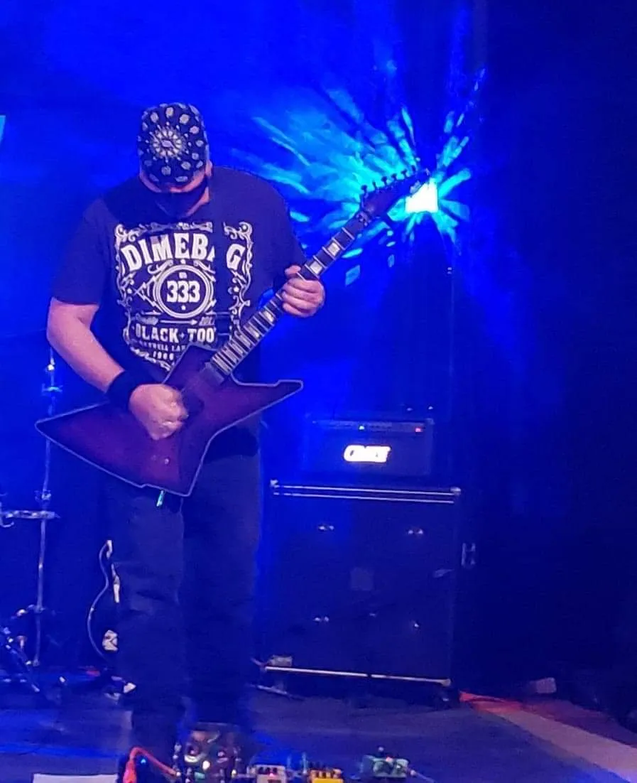 Ace Parlier playing guitar on stage under blue light